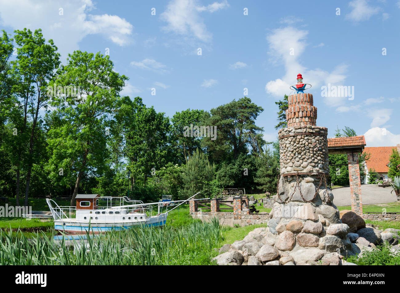 stilisierte Stein Leuchtturm am Fluss mit alten Touristenboot Stockfoto