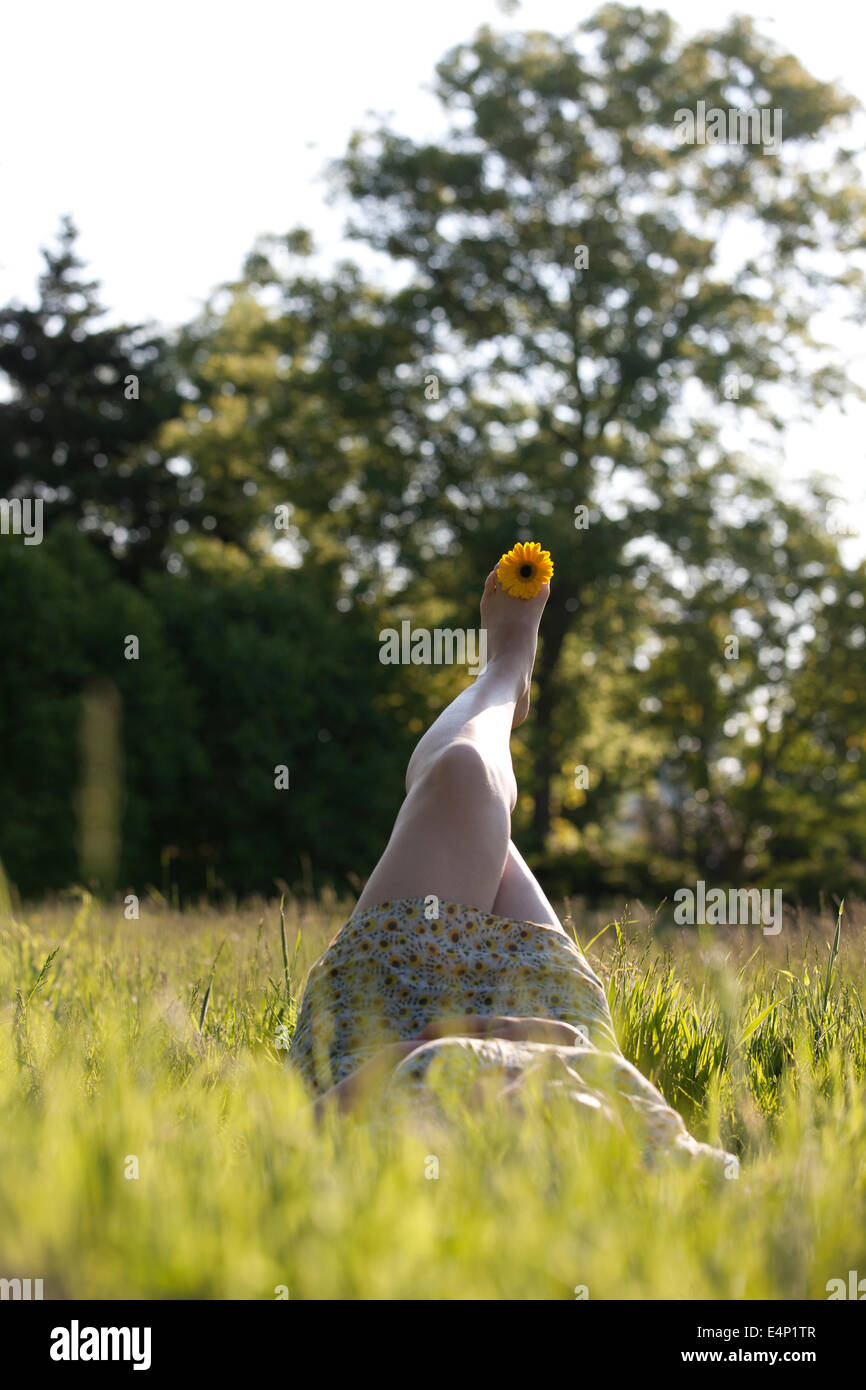 Eine junge Frau im Gras mit ein gelbes Gänseblümchen zwischen den Zehen Stockfoto