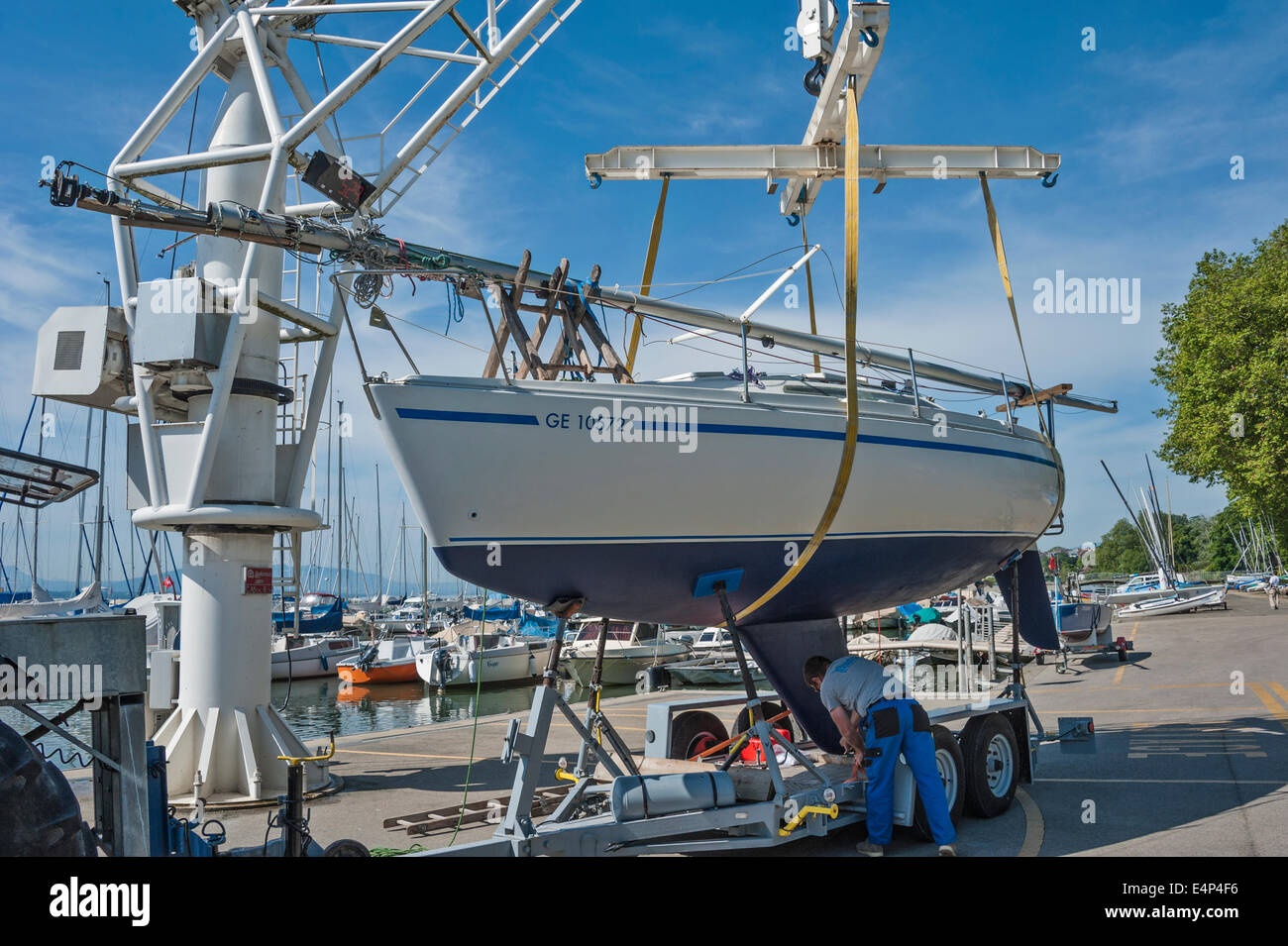 Ein Mann, heben Sie eine Segelyacht seine Anhänger mit einem Kran in einem Hafen wird vorbereitet Stockfoto