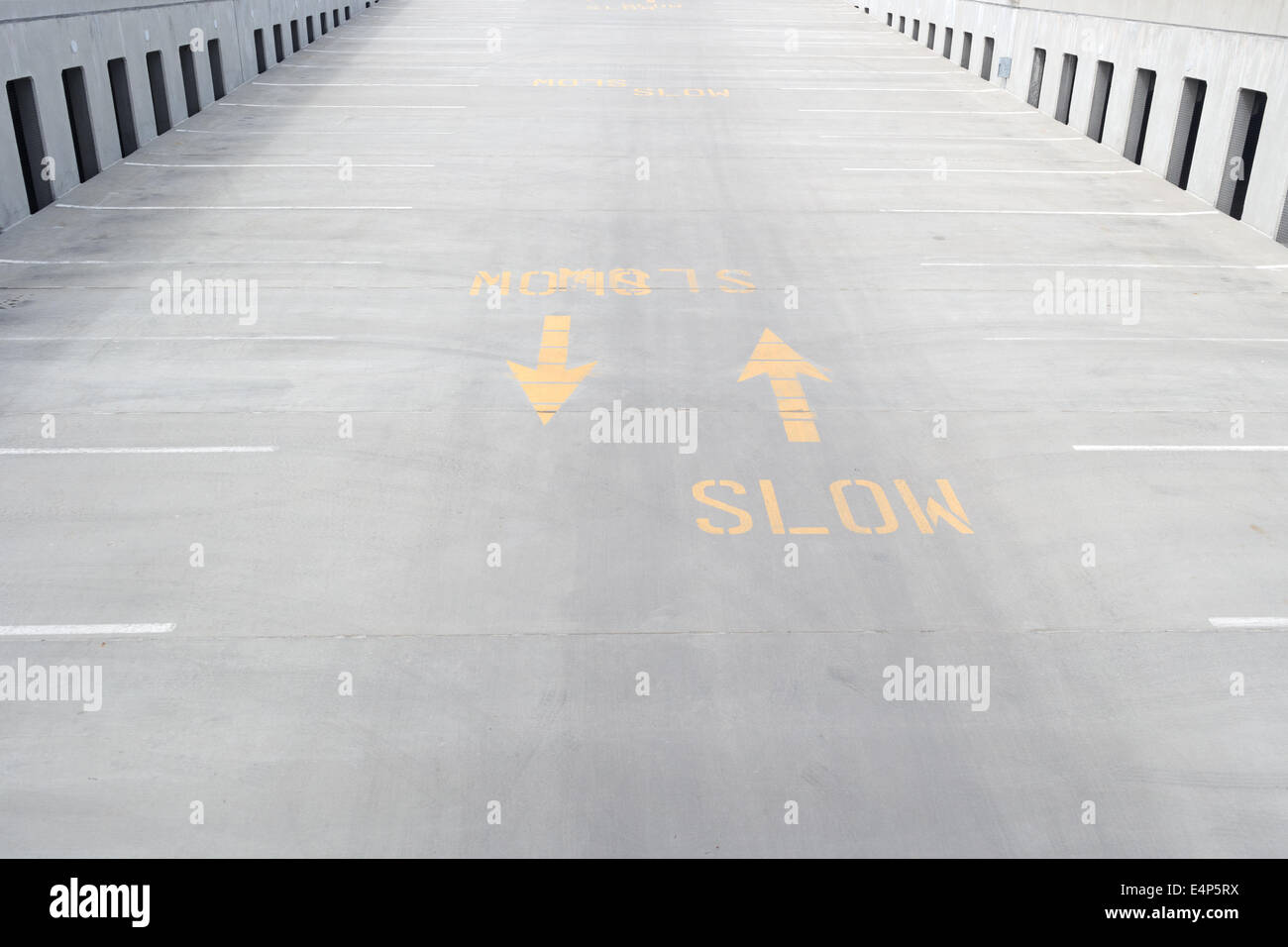 Ein helles Gelb langsamere Zeichen auf eine konkrete Ausfahrt mit Pfeilen gedruckt. Stockfoto
