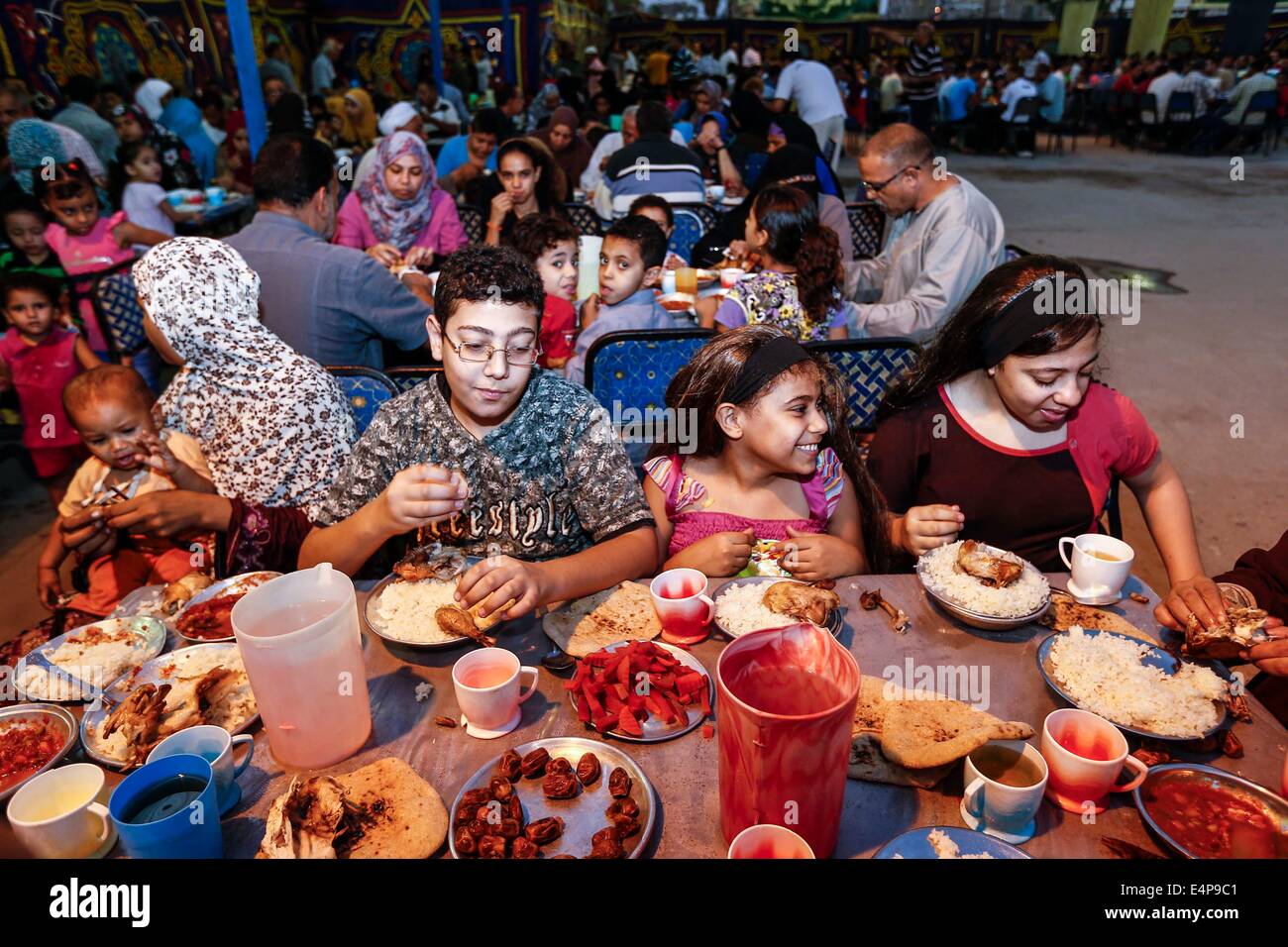Kairo, Ägypten. 15. Juli 2014. Ägypter genießen Sie ihre Mahlzeiten bei einem Charity-Bankett in Kairo, Ägypten, 15. Juli 2014. Nächstenliebe Bankette oder ma'idat al-Rahman, eine langjährige Tradition der Ramadan in Ägypten, vertreten durch die wohlhabende Gönner ihre weniger wohlhabenden Glaubensgenossen zu den Mahlzeiten bieten, das Fasten zu brechen. © Cui Xinyu/Xinhua/Alamy Live-Nachrichten Stockfoto