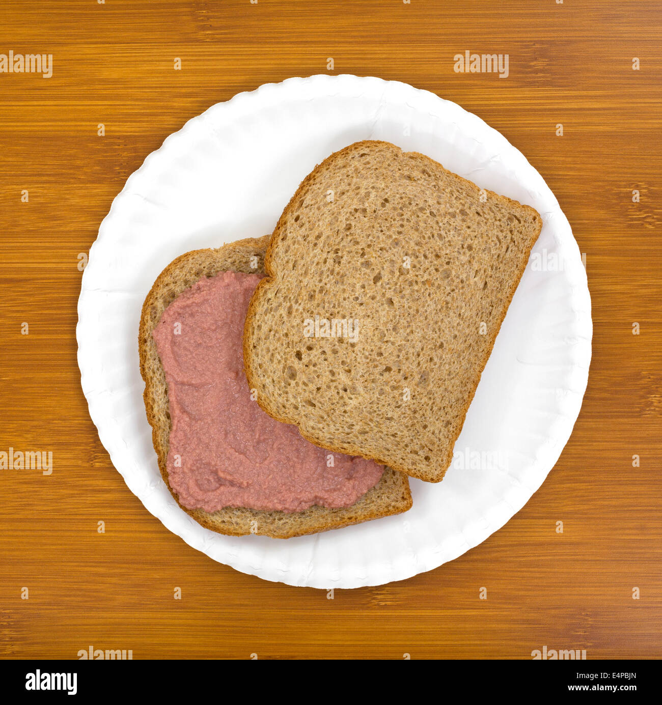 Draufsicht eines eingemachte Fleisch-Sandwiches mit Vollkornbrot auf einem weißen Teller oben auf einem Holztisch. Stockfoto