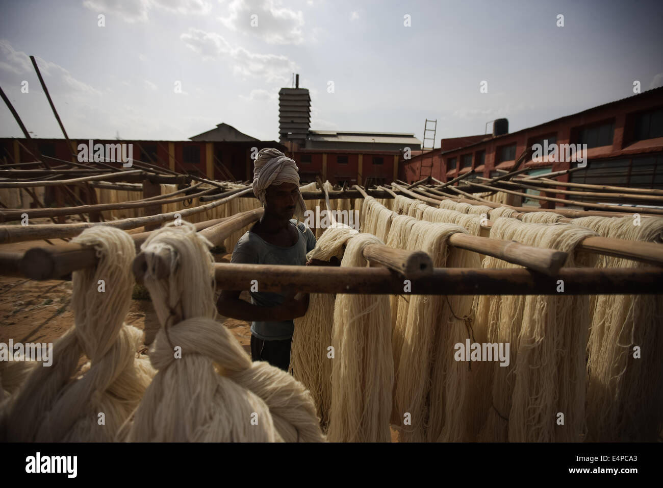 Rajasthan, Rajasthan in Indien. 15. Juli 2014. Ein Mann trocknet die Wolle an einer Wollfabrik in Bikaner, Rajasthan Indien, 15. Juli 2014. Dank der Bikaner Magra Schaf- und Chokhla Schafe, die als nur glänzende Teppich Wolle produzierenden Rassen bekannt sind, wurde die Wollindustrie von Bikaner ein profitables Geschäft, obwohl die Fabriken alte Maschinen verwenden. © Zheng Huansong/Xinhua/Alamy Live-Nachrichten Stockfoto