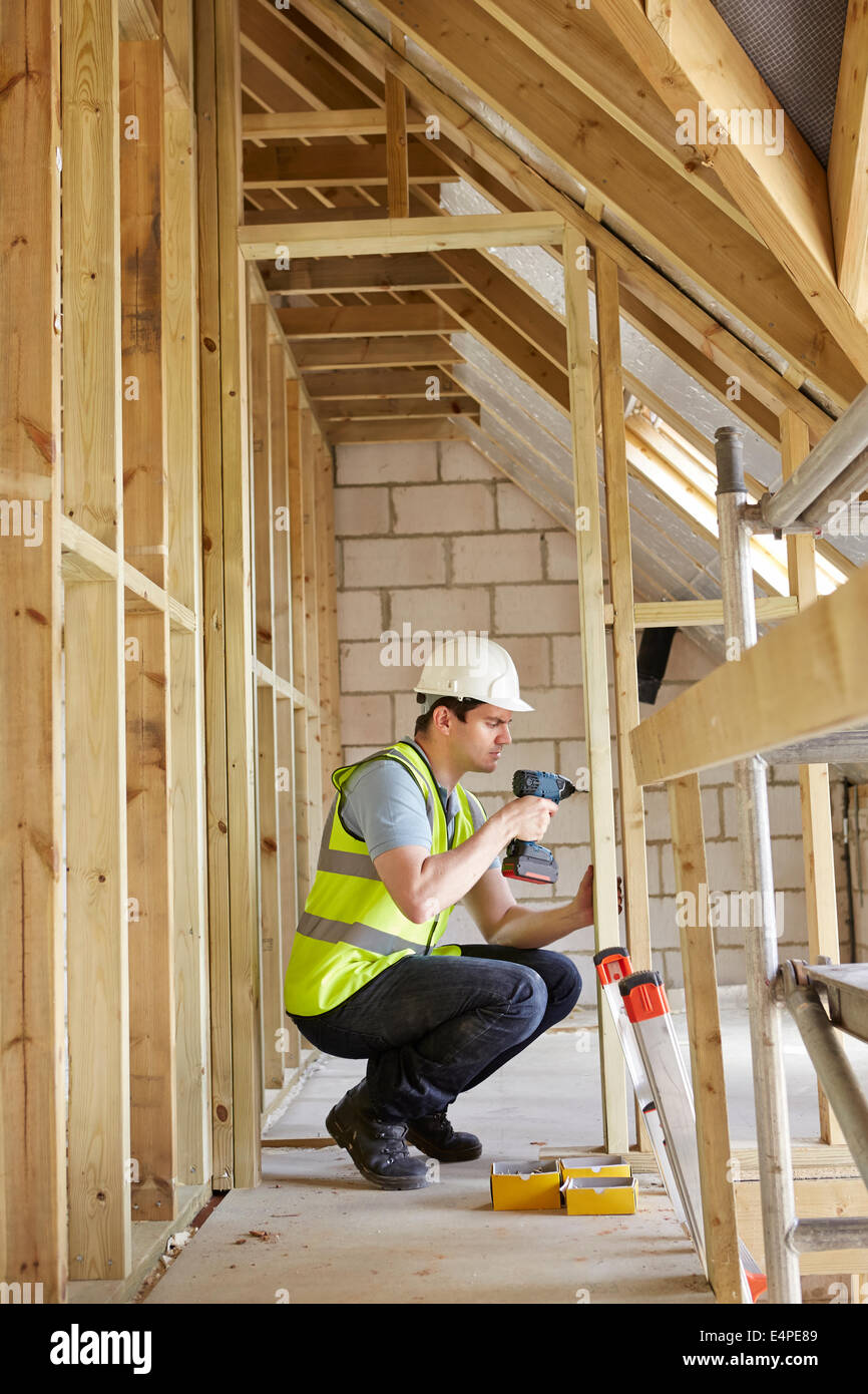 Bauarbeiter mit Bohrer auf Haus bauen Stockfoto