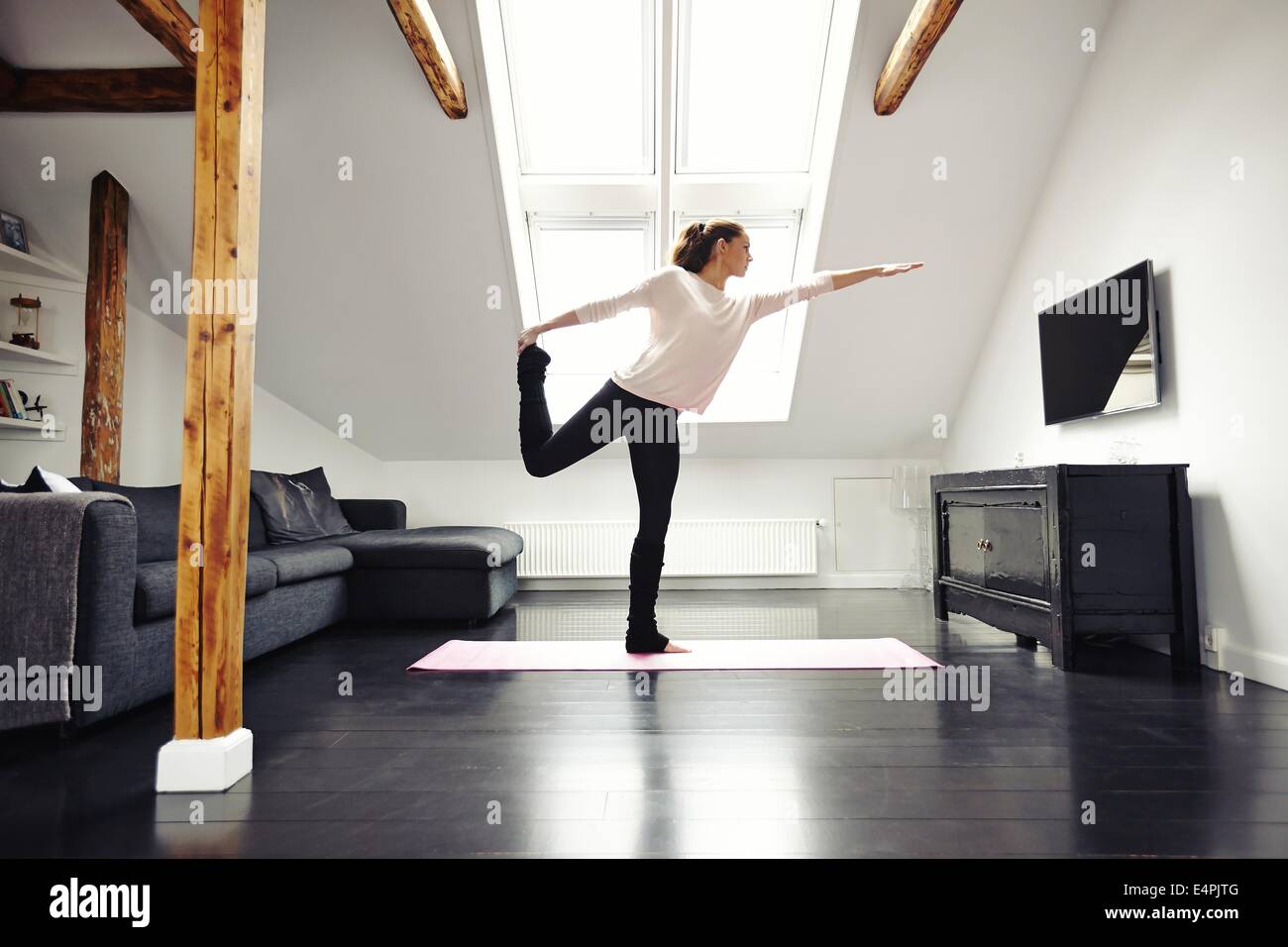 Fitness Frauen Gymnastik im Wohnzimmer. Stretching und balancieren auf einem Bein zu Hause. Kaukasischen Frauen Yoga zu praktizieren. Stockfoto