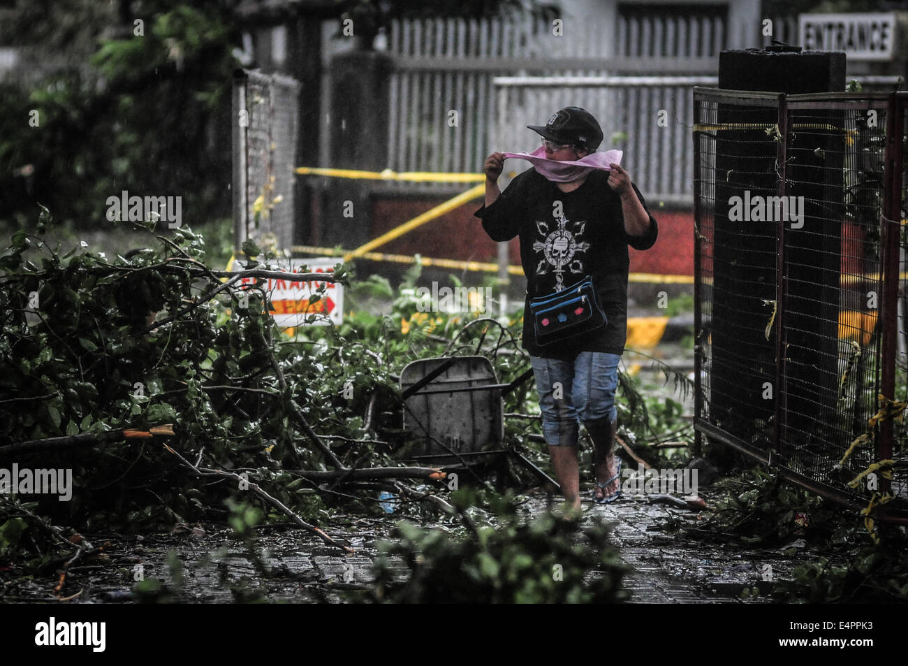 Manila, Philippinen. 16. Juli 2014. Eine Frau geht durch umgestürzten Baum Zweige entlang einer Straße in Manila als Taifun Glenda, internationalen Namen Rammasun, durch die Stadt am 16. Juli 2014 prügelt. Taifun Rammasun Herunterfahren der philippinischen Hauptstadt am 16. Juli, wie Behörden, den ersten großen Sturm das Land brutal Regenzeit beanspruchten mindestens vier Leben sagte und zwang Hunderttausende zu evakuieren. Bildnachweis: George Calvelo/NurPhoto/ZUMA Draht/Alamy Live-Nachrichten Stockfoto