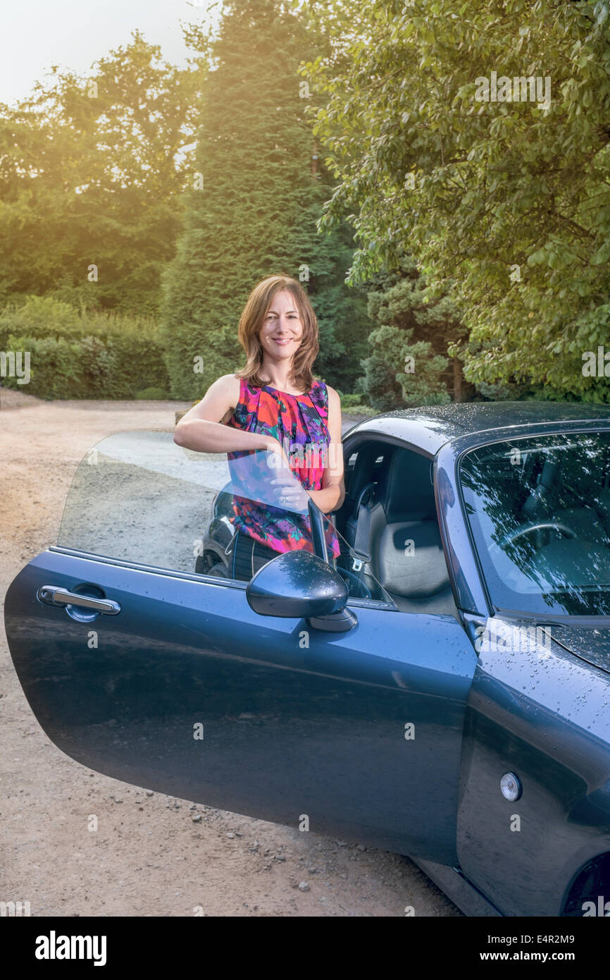 Attraktive mittlere gealterte Frau stehen neben ihrem Sportwagen. Stockfoto