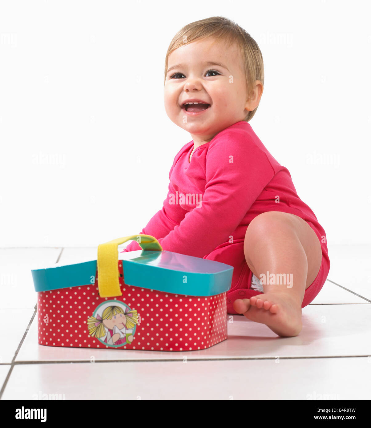 Babymädchen (12 Monate) neben Spielzeug-Picknick-Korb Stockfoto