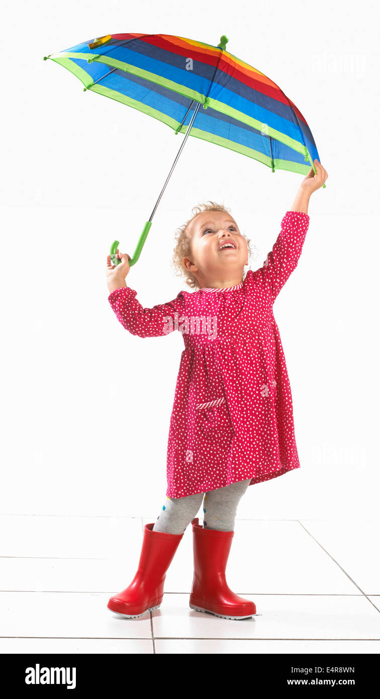 Kleine Mädchen (2 Jahre) in Gummistiefel und Holding-Dach Stockfoto