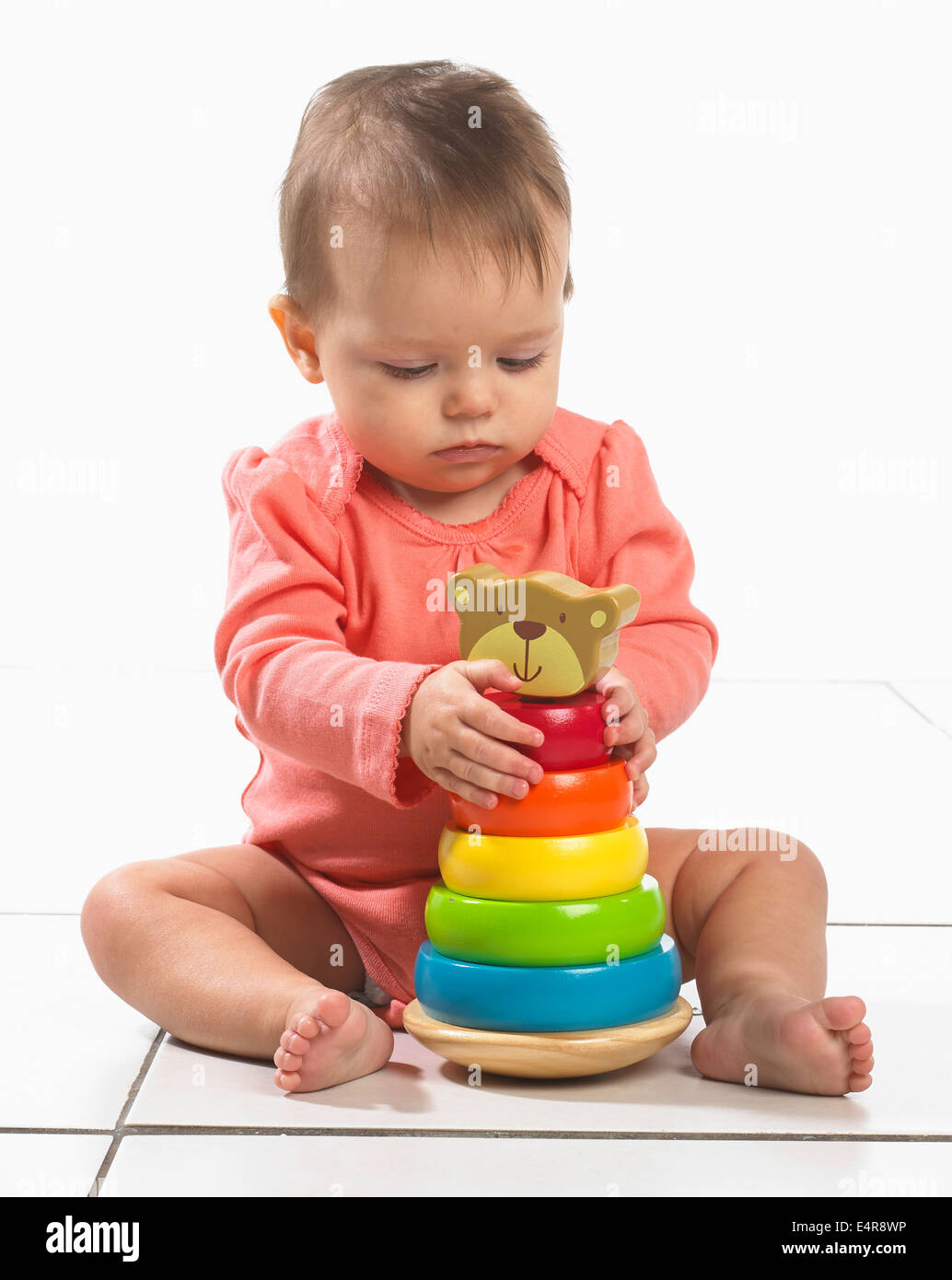 Baby Girl (8 Monate) mit bunten Stapeln Ring Spielzeug spielen Stockfoto