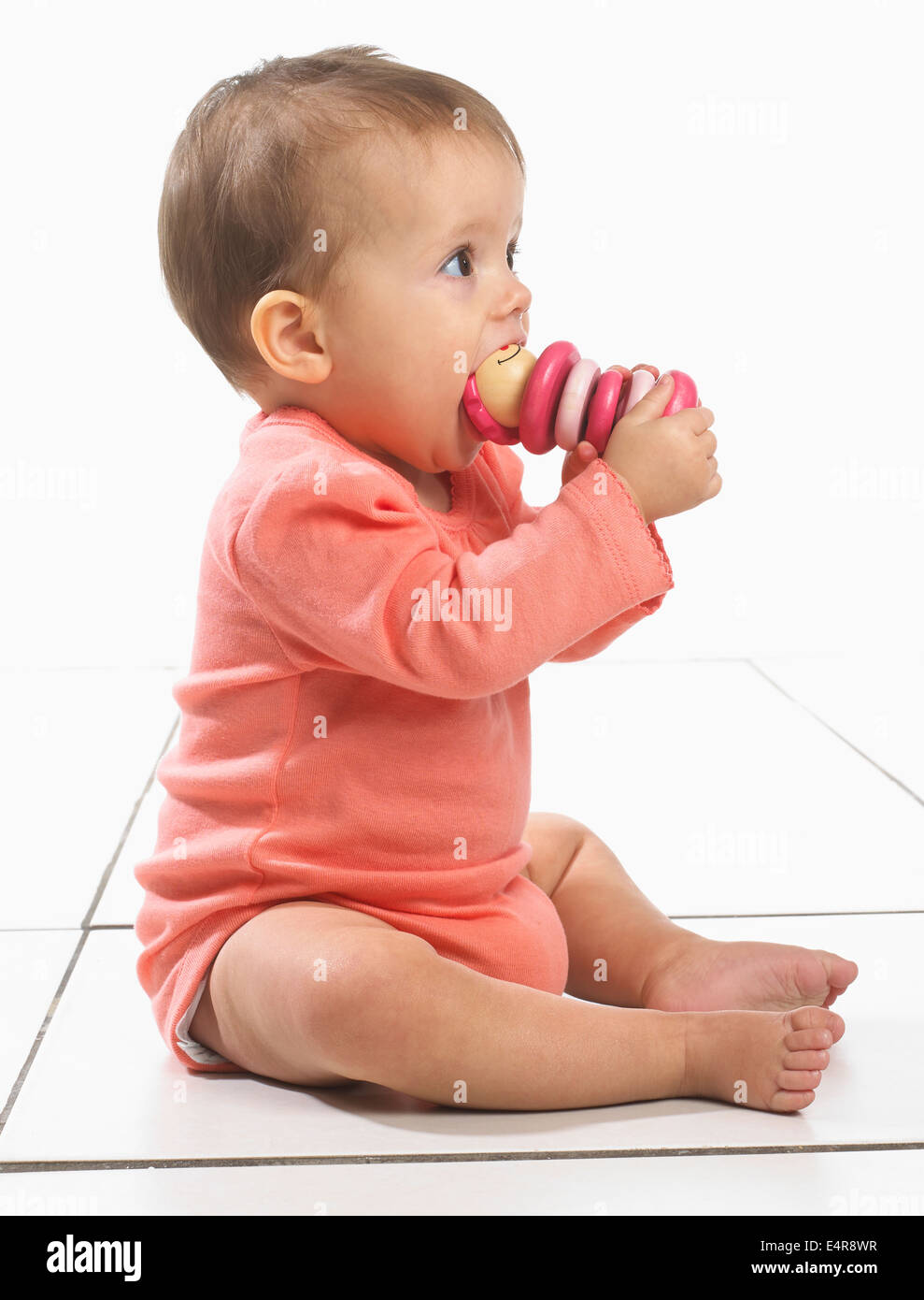 Baby Girl (8 Monate) mit Spielzeug im Mund Stockfoto