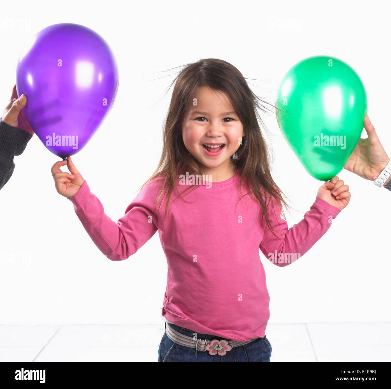 Mädchen (3,5 Jahre) steht das Lachen als ihr Haar klebt mit statischer Elektrizität, zwei Ballons Stockfoto