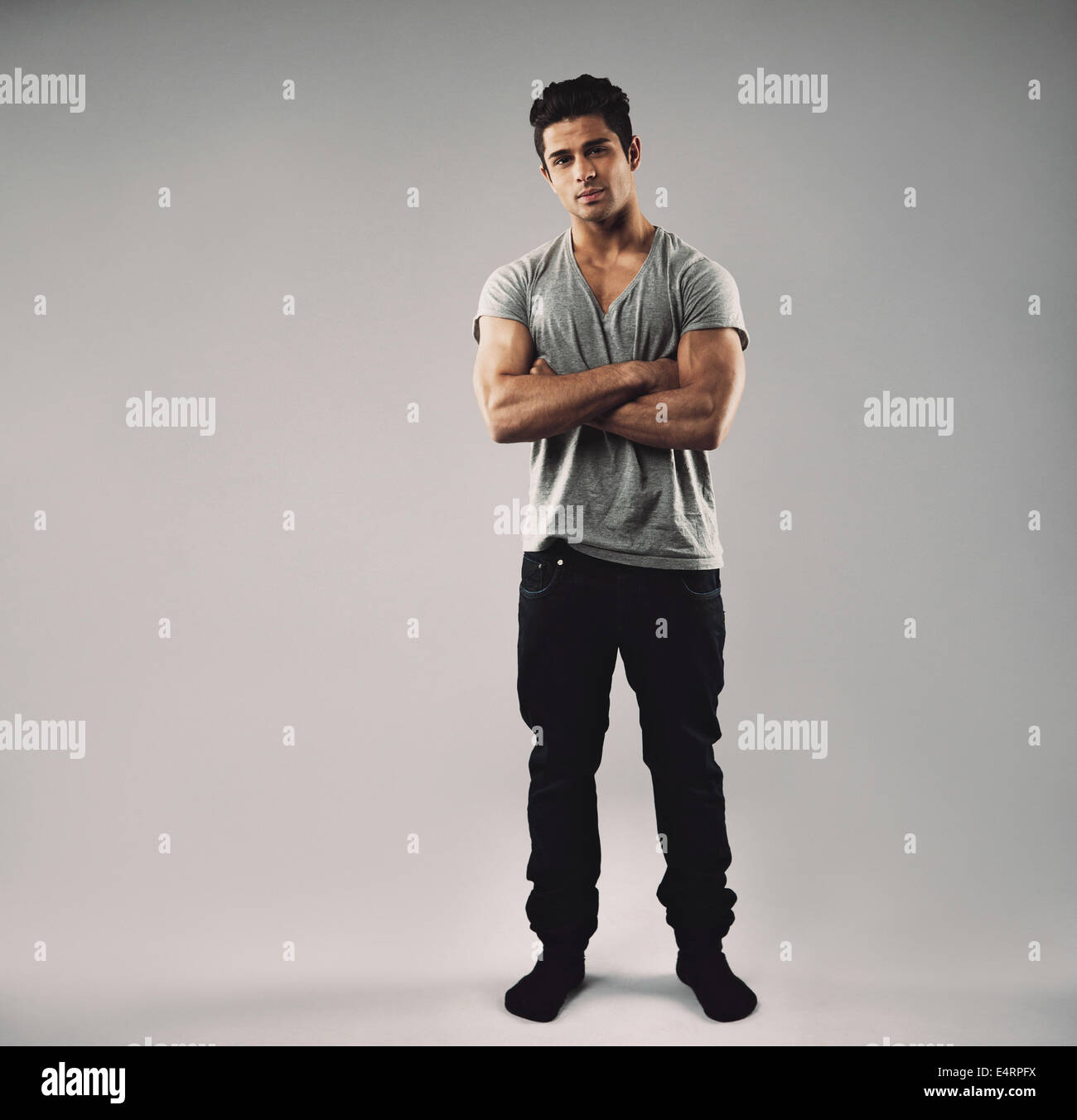 In voller Länge Portrait von muskulösen jungen Mann mit seine Arme verschränkt. Hispanische Mate Modell Casuals mit Textfreiraum. Stockfoto