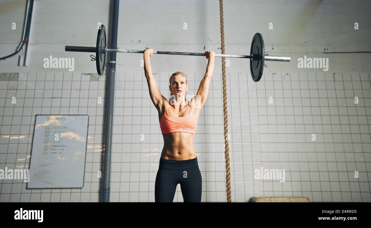 Muskulöse junge Sportlerin Gewichtheben bei Crossfit Gym zu tun. Junge Frau Modell Heben schwerer Gewichte im Fitnessstudio angepasst. Stockfoto