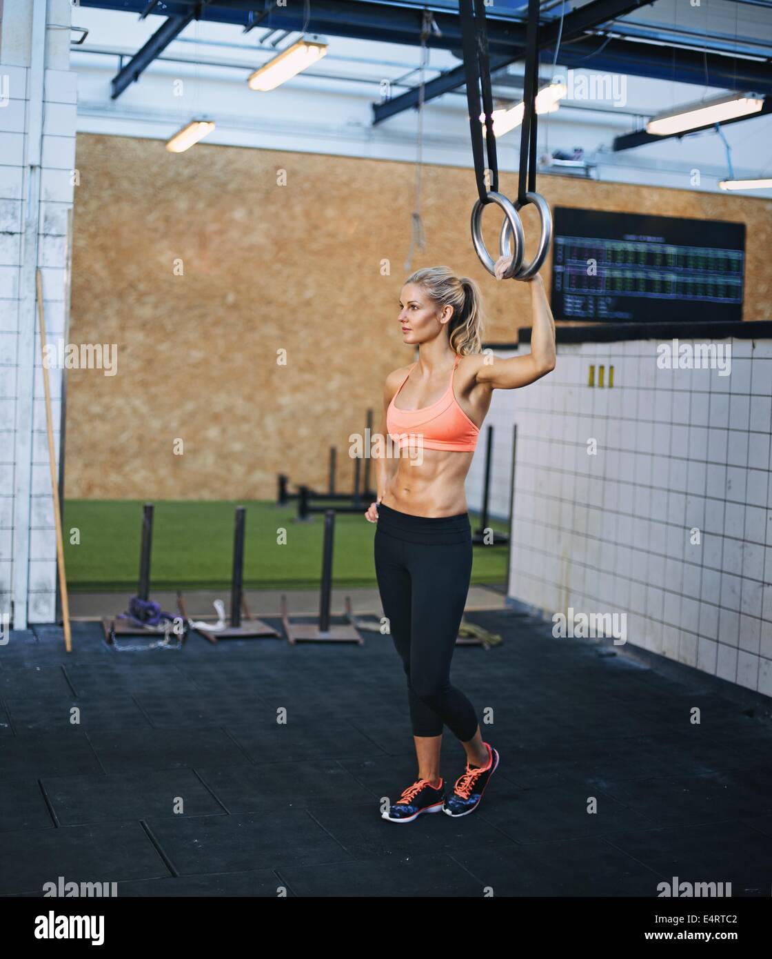 Muskulöse Sportlerin holding Turnerin Ringe in der Turnhalle. Kaukasische Mädchen trainieren im Fitnessraum mit Ringen. Stockfoto