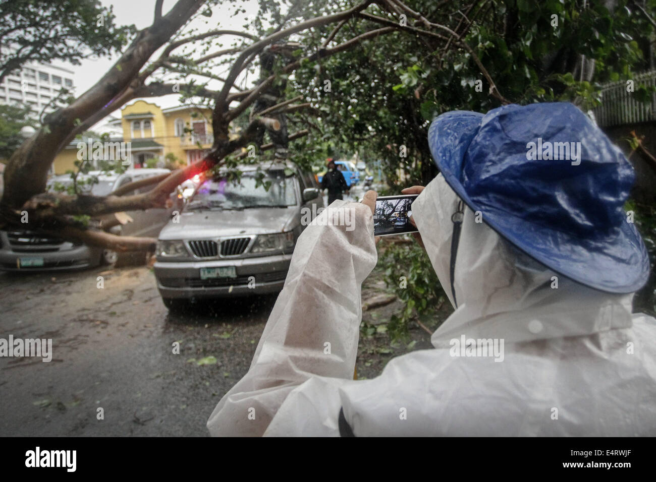 Manila, Philippinen. 16. Juli 2014. Ein Mann nimmt ein Bild von beschädigten Autos in der Nähe von einem privaten Unterteilung in Makati City, wie Taifun Rammasun Metro Manila am 16. Juli 2014 getroffen. Taifun Rammasun (lokal bekannt als Glenda) hatte maximale Windgeschwindigkeiten von 150 km/h und Böen von bis zu 185 km/h, wenn es Metro Manila getroffen. Über das Land hatte etwa 400.000 Menschen aus ihren Häusern geflohen und geschützt in Evakuierungszentren, nach der Katastrophe-Vorstandes. Bildnachweis: ZUMA Press, Inc./Alamy Live-Nachrichten Stockfoto