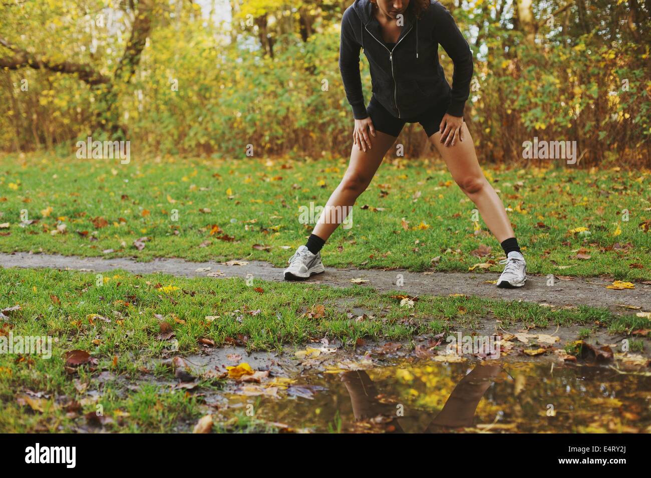 Junge kaukasische Athletin, die sich im Herbst im Park dehnt. Fitness-Frau, die im Freien trainiert Stockfoto