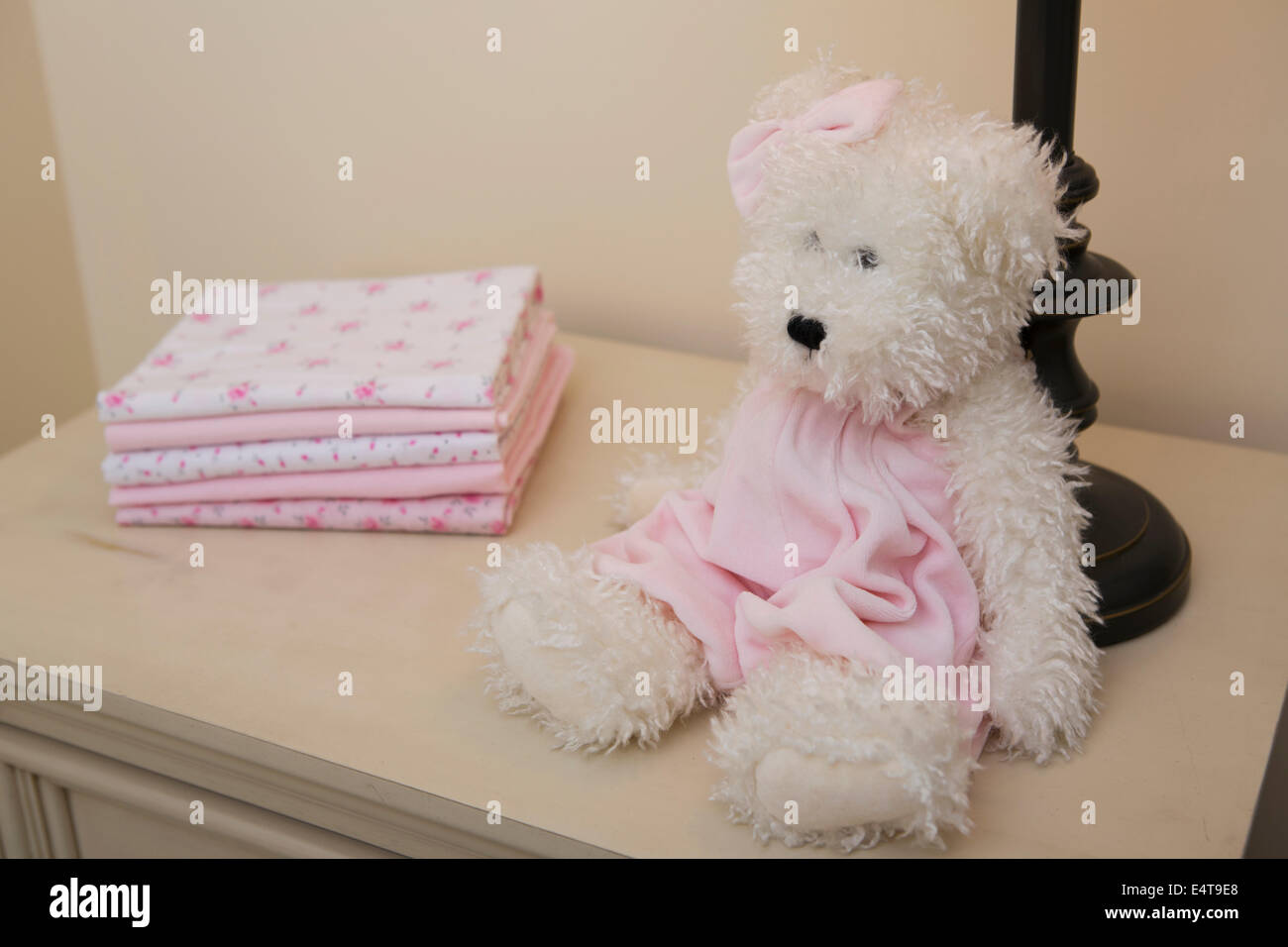 Stapel von Babydecke auf Kommode neben Teddybär und Lampe im Kinderzimmer Stockfoto