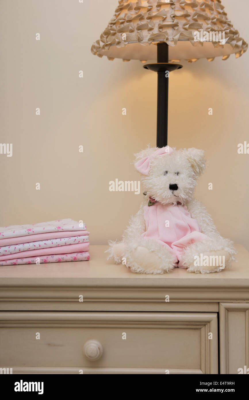 Stapel von Babydecke auf Kommode neben Teddybär und Lampe im Kinderzimmer Stockfoto