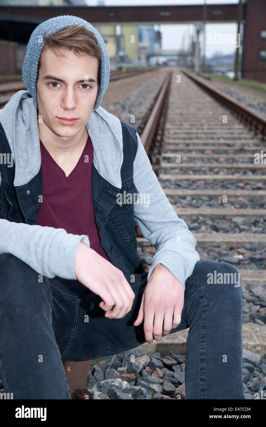 Porträt von Teenager sitzen auf Eisenbahnschienen, Blick in die Kamera, Deutschland Stockfoto