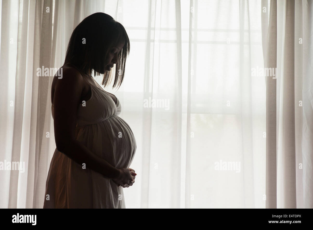 Silhouette der schwangeren Frau Fenster stand Stockfoto