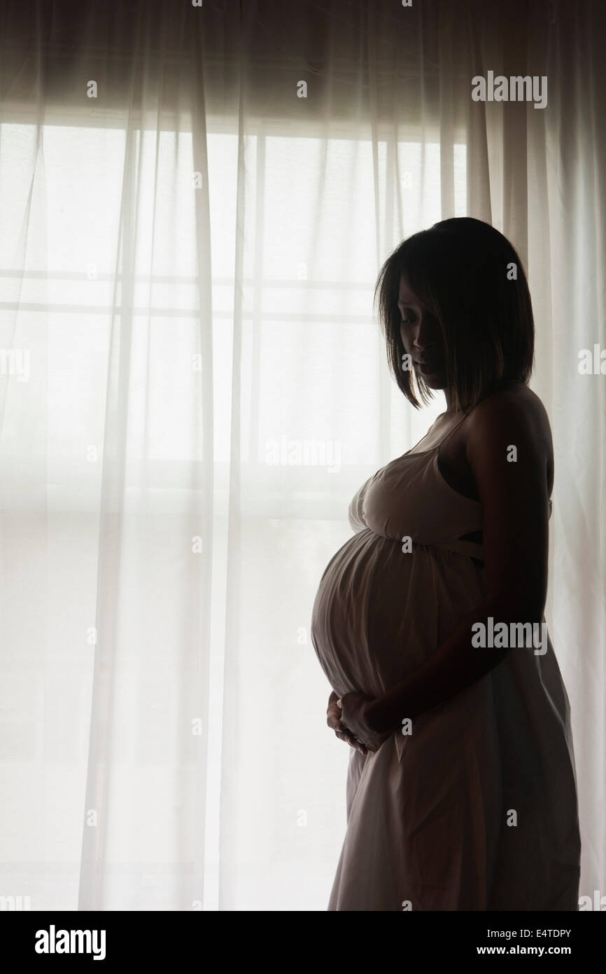 Silhouette der schwangeren Frau Fenster stand Stockfoto