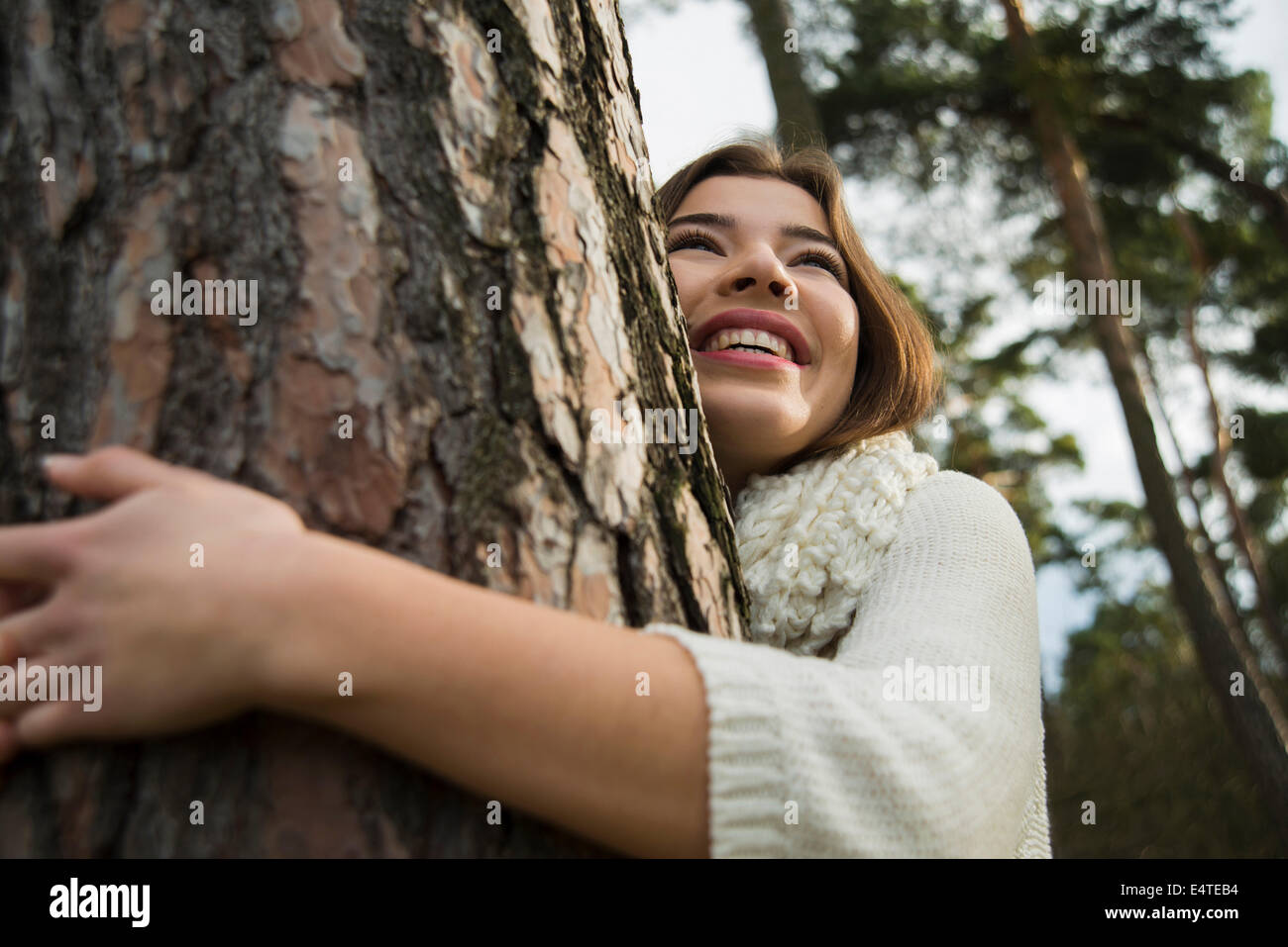 Junge Frau umarmt Tree Trunk, Mannheim, Baden-Württemberg, Deutschland Stockfoto
