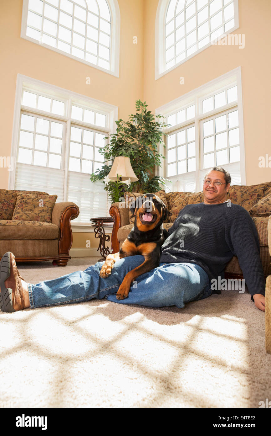 Porträt von reifer Mann mit seinem Haustier Rottweiler im Wohnzimmer Stockfoto