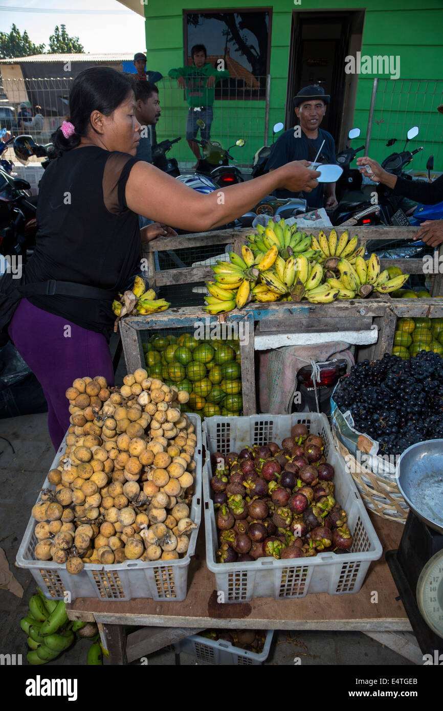 Bali, Indonesien.  Obstverkäufer im lokalen Markt.  Mangostanfrüchte in Papierkorb, vorne rechts. Stockfoto