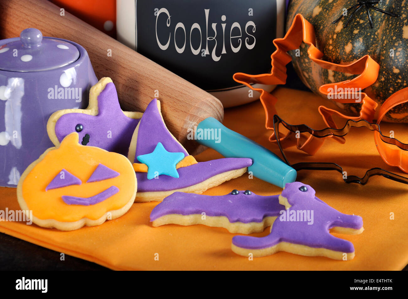 Happy Halloween-Party hautnah Süßes oder Saures Cookies mit Nudelholz, Ausstechformen und Keksdose - lila und orange. Stockfoto