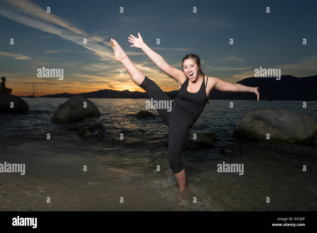 Fröhliche junge Frau am Strand bei Sonnenuntergang. Stockfoto