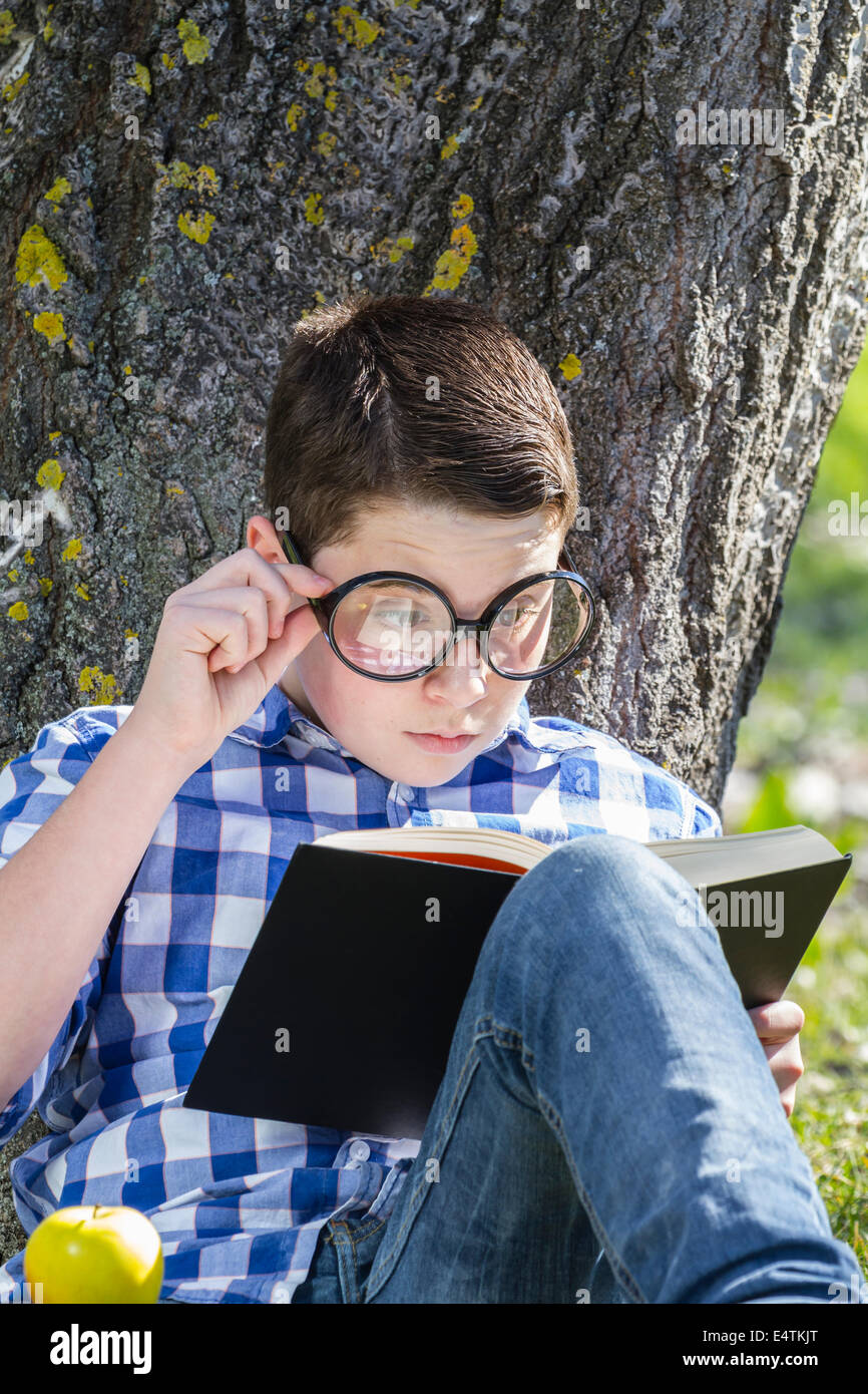 Kleiner Junge liest ein Buch im Wald mit geringer Tiefe Feld und Kopie