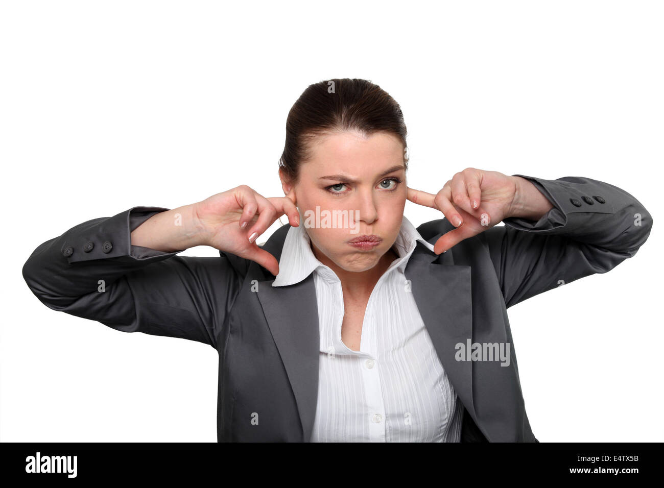 Brünette Büroangestellte mit den Fingern in den Ohren Stockfoto