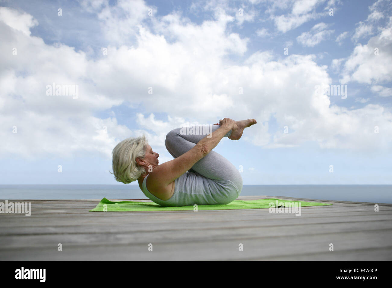 ältere Frau macht Übungen am Strand Stockfoto
