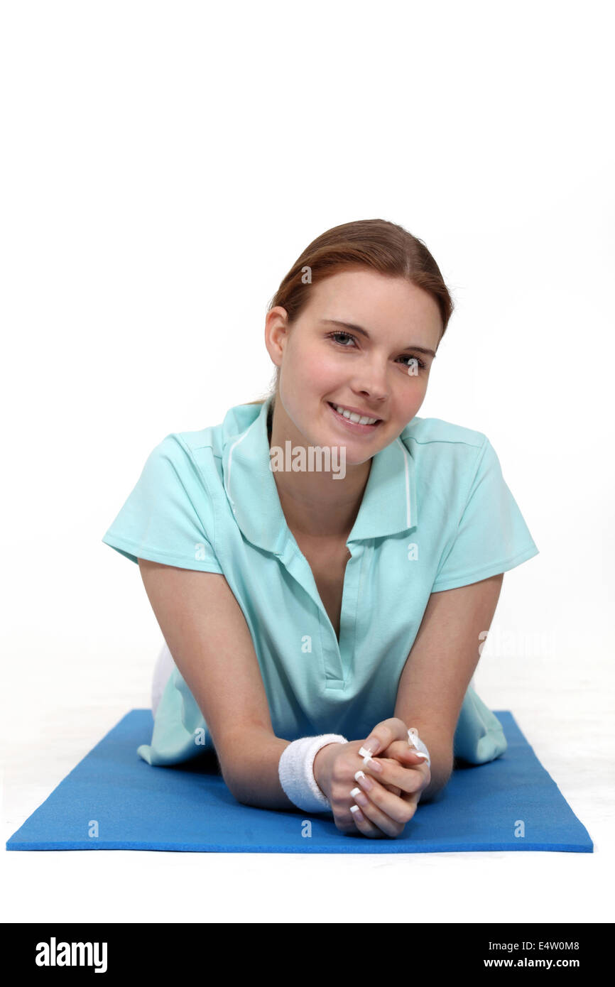Frau liegend auf einer Yogamatte Stockfoto
