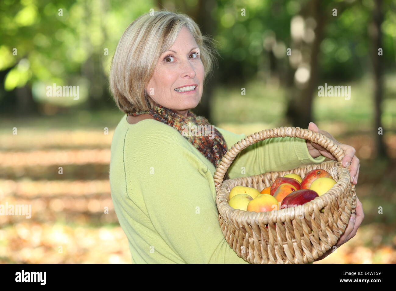 Reife blonde Frau im Obstgarten Stockfoto