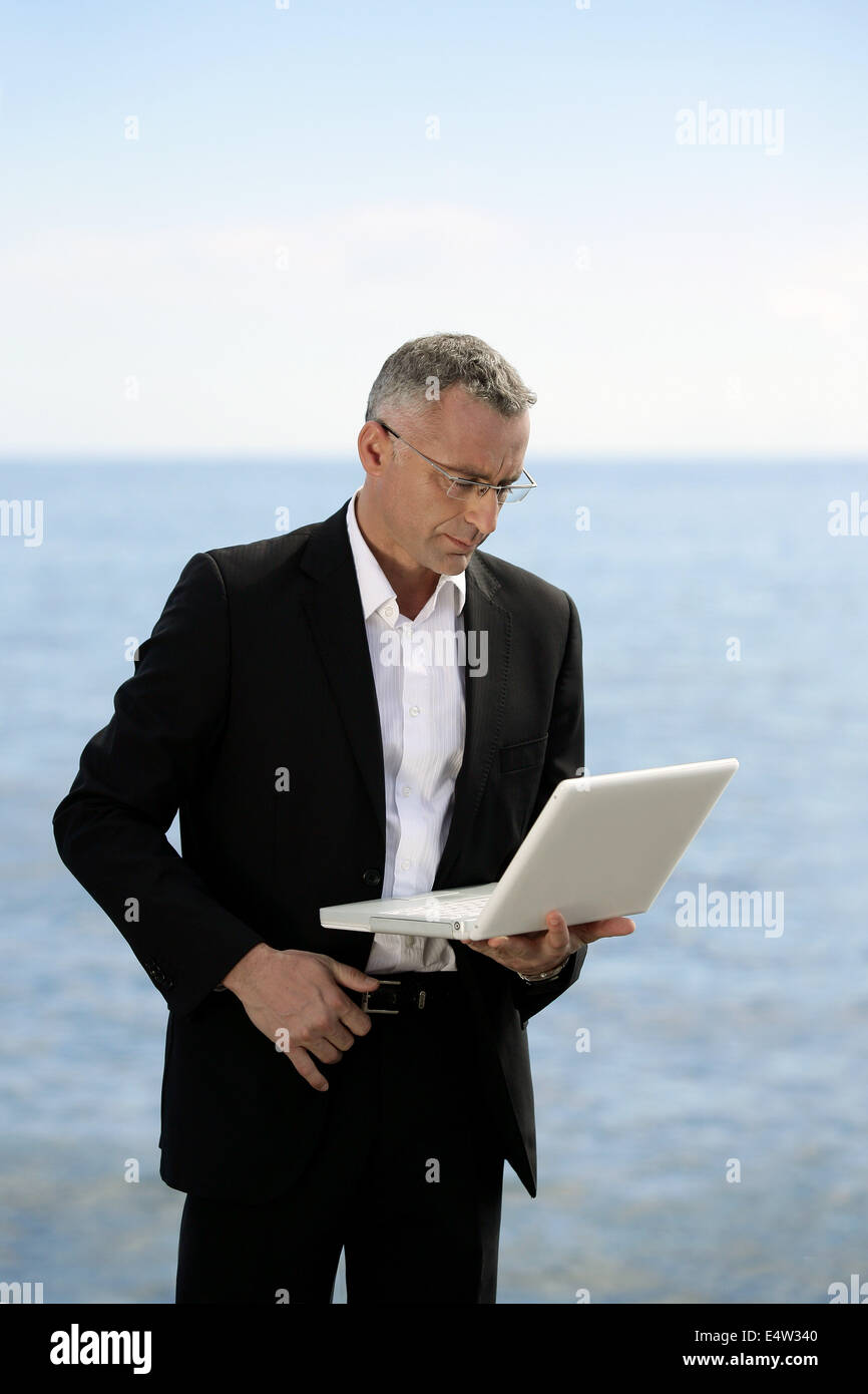 Geschäftsmann mit Laptop Stand See Stockfoto
