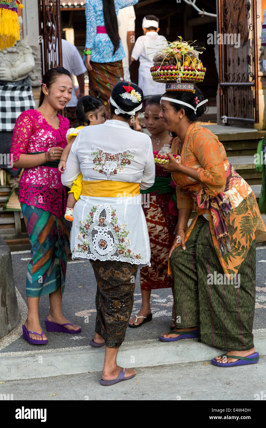 Bali, Indonesien.  Frauen und Kindern im Gespräch am Eingang zu einem Tempel. Stockfoto