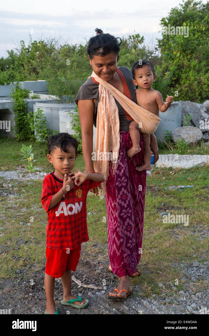 Bali, Indonesien.  Balinesischen Mutter und Kinder, tragen die jüngste in einem Schulter-Riemen. Stockfoto