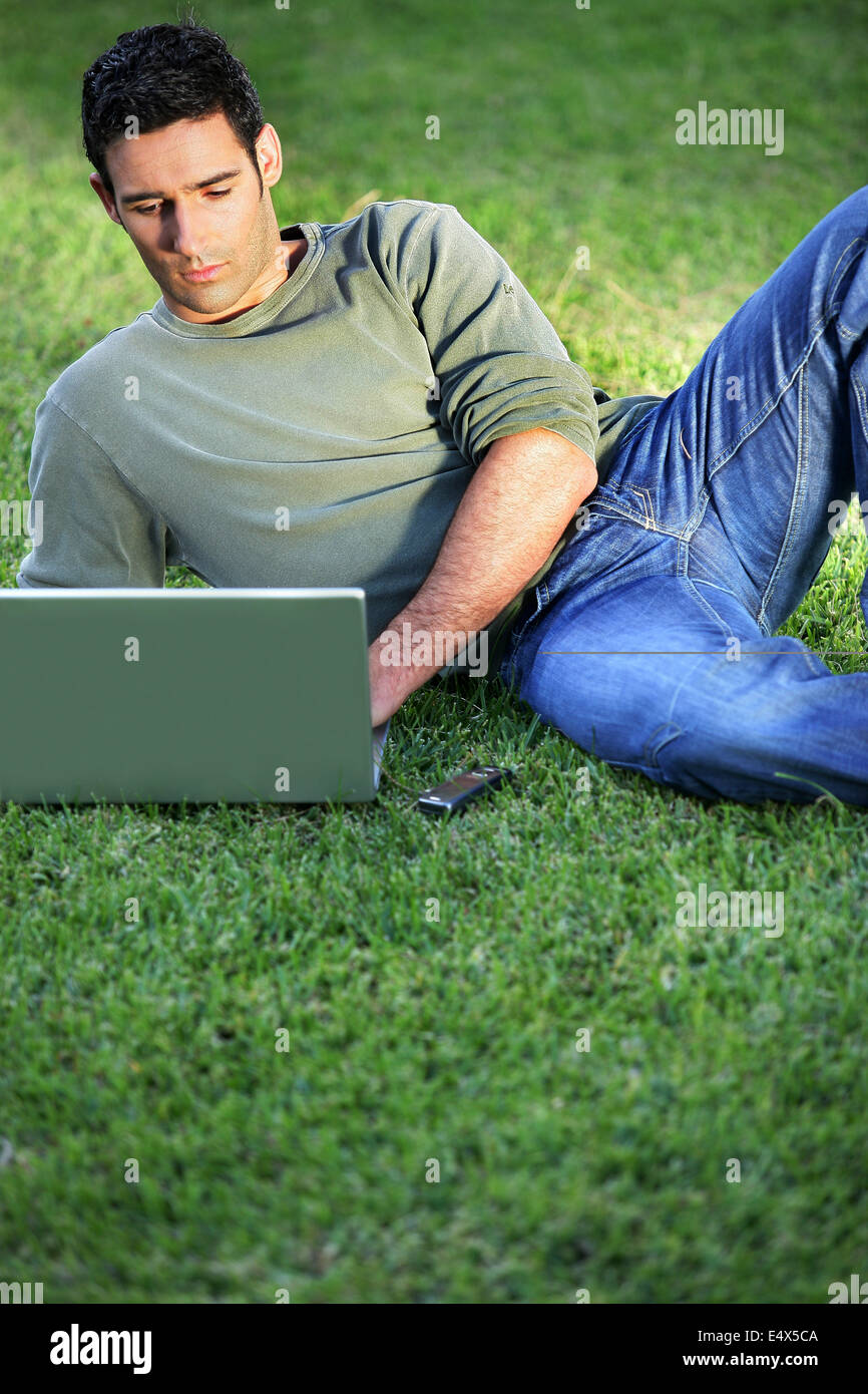 Mann liegt auf dem Rasen vor laptop Stockfoto
