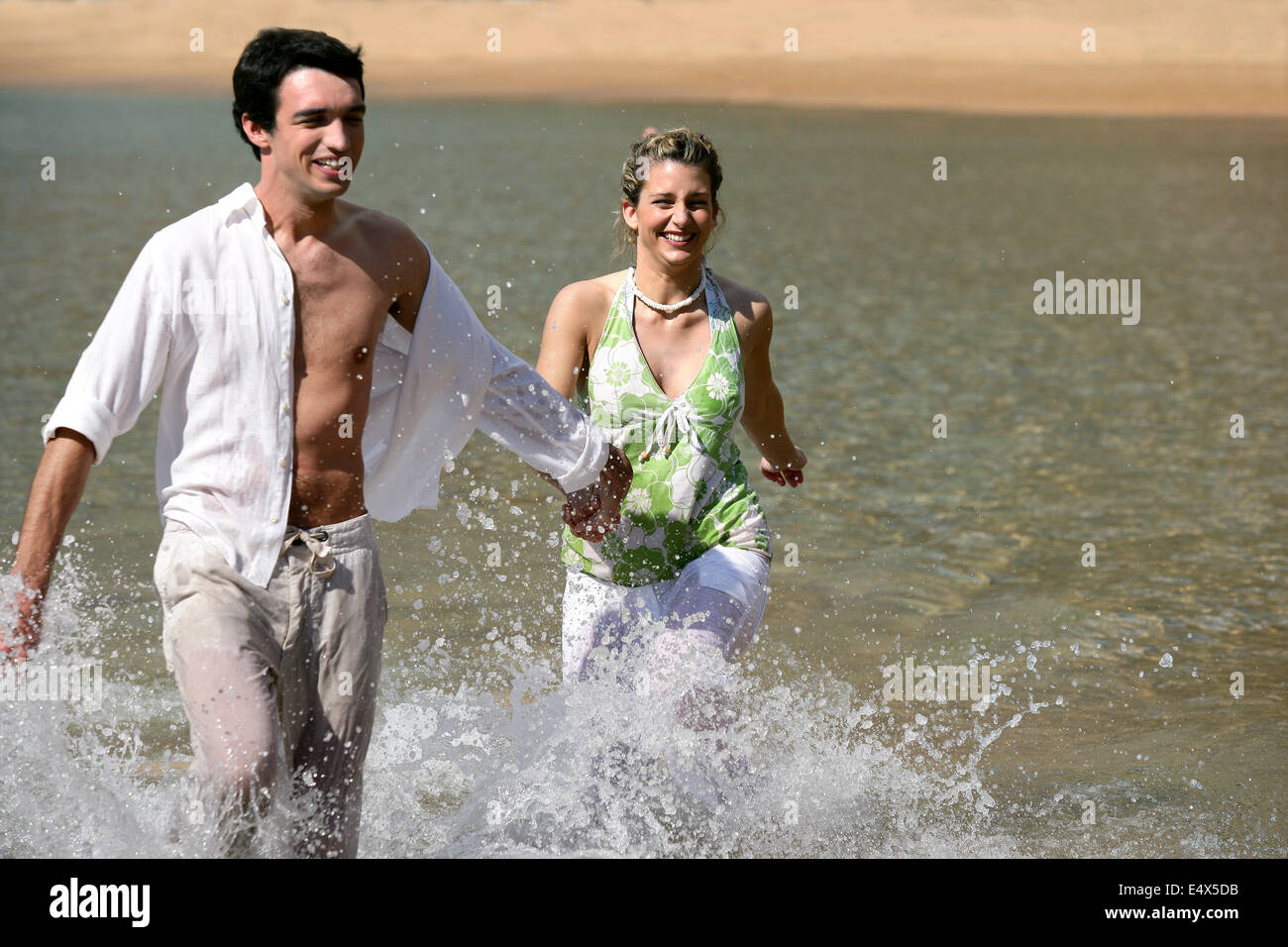 Verspielte junge Paar laufen durch Wasser Stockfoto