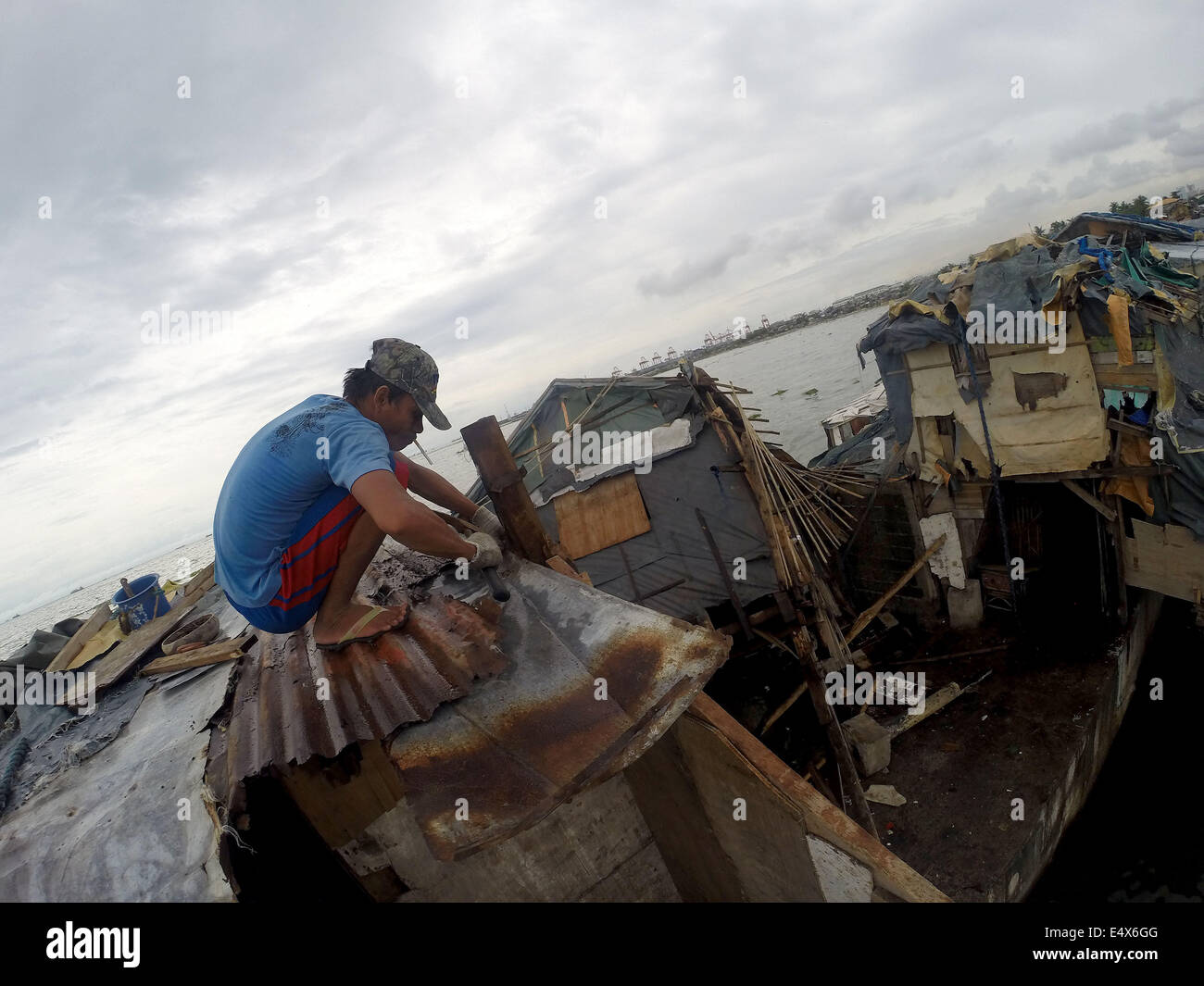 Manila, Philippinen. 17. Juli 2014. Ein Mann repariert das Dach seines Hauses, nachdem es durch Taifun Rammasun an einem Slumviertel in Manila, Philippinen, am 17. Juli 2014 beschädigt worden war. Die Zahl der Todesopfer durch Taifun Rammasun stieg auf 38, die lokale Katastrophe Agentur sagte am Donnerstag. Die National Disaster Risk Reduction and Management Council (NDRRMC) sagte, dass der Taifun auch linken 10 Verletzte während acht andere deklariert wurden vermisst. Bildnachweis: Rouelle Umali/Xinhua/Alamy Live-Nachrichten Stockfoto