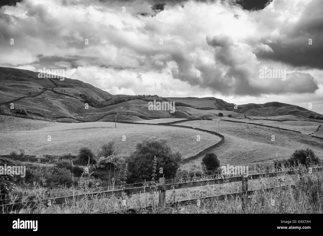 Blick über hügelige Ackerland mit Trockenmauern und Post und Zaun im Vordergrund Stockfoto