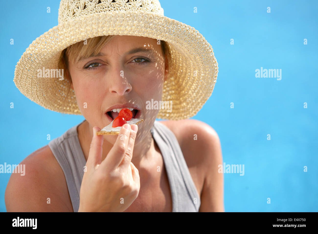 Frau im Strohhut Essen Erdbeere Stockfoto