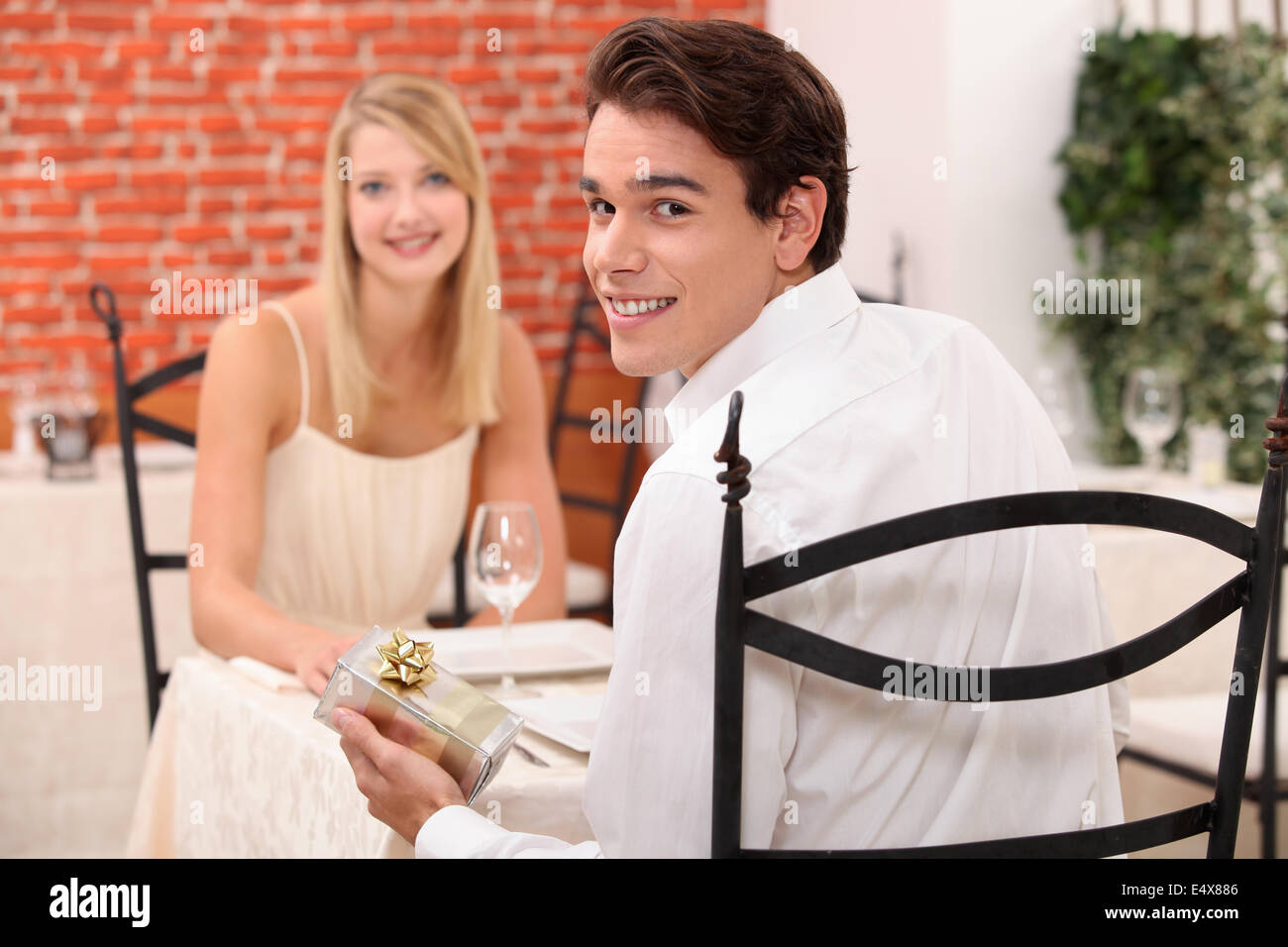 Paar im Restaurant mit Geschenk Stockfoto