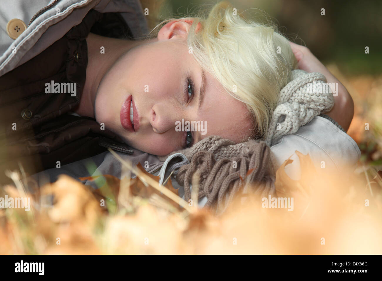 Blonde Frau, die Verlegung in Blättern Stockfoto