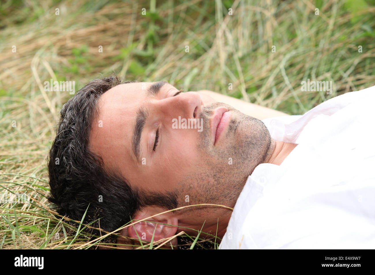 Mann schläft auf dem Rasen Stockfoto