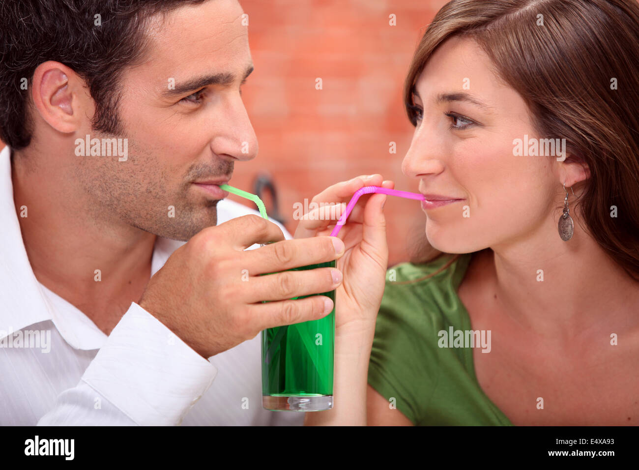 Paar aus demselben Glas trinken Stockfoto