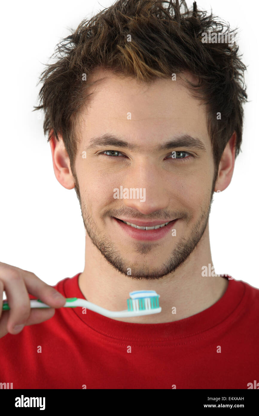 Junger Mann hält eine Zahnbürste Stockfoto