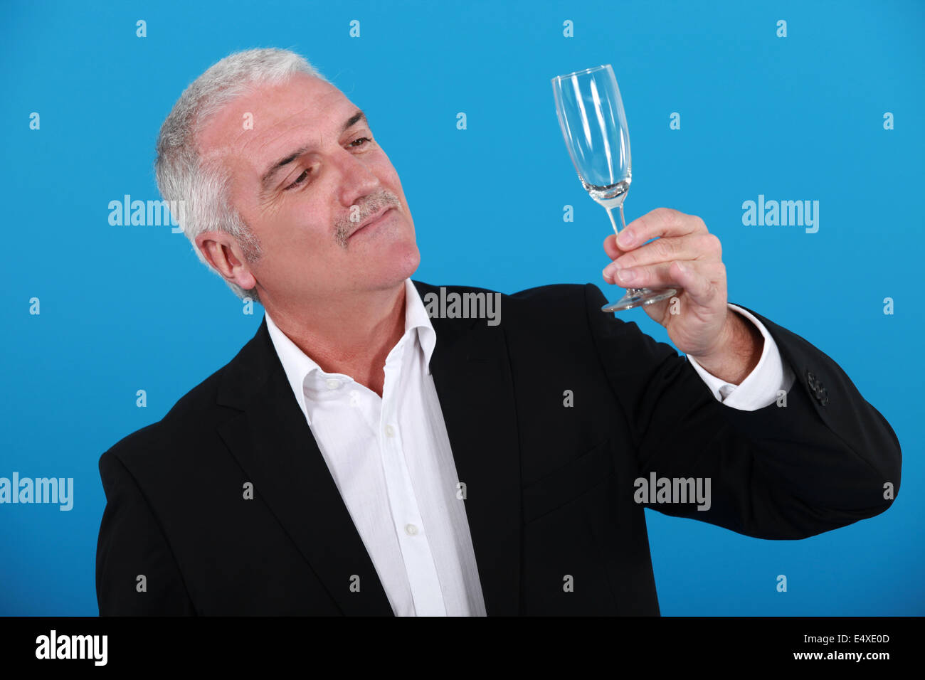 Grauhaarige Mann hält Sektflöte "Soirée" Stockfoto